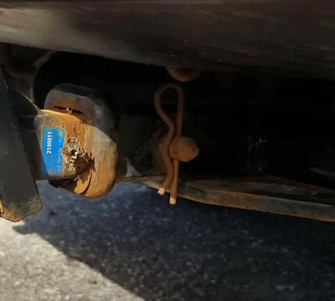 Close-up of a rusted 5/8 inch by 4.25 inch trailer hitch pin, installed on a vehicle, showing corrosion on zinc plating and pin.