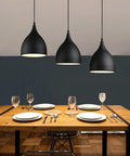 Dark Antique Farmhouse Pendant Light with Single Hanging Shade illuminating a dining table setup with plates.