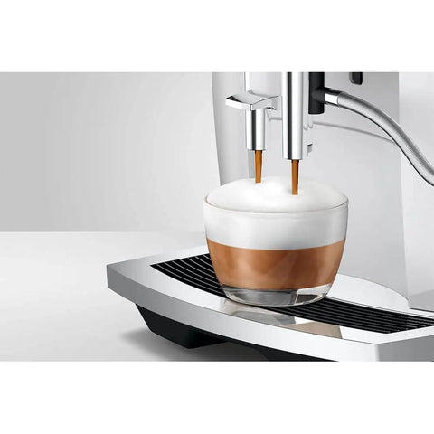 No Sweat Automatic Coffee Maker With Smart Touchscreen And Adjustable Steaming Settings Piano White Finish brewing espresso into a glass cup.