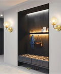 Lit Water Ripple Lampshade Double Gold Wall Sconce Set illuminating a modern hallway with seating and decor.