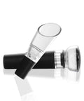Transparent wine pourer and black stopper set, close-up view on reflective surface.
