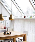Contemporary dining area with modern pendant lights and a wooden table, featuring a stylish window design.