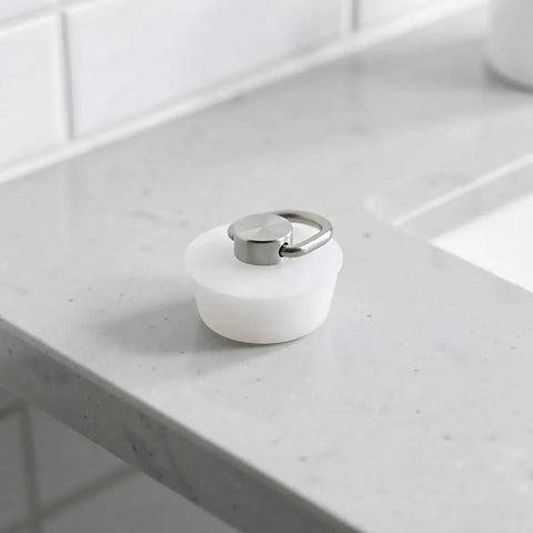 White Drain Sealing Plug Silicone Bathtub Stopper with Ring on a marble countertop, showcasing its clean design and practical use.