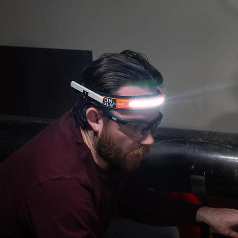 Person wearing Rechargeable Wide Beam Headlamp With Strap And 575 Lumens Five Lighting Modes All Day Runtime Direct Focus And Hard Hat Compatibility For Work And Outdoor Adventures while working in dark environment.