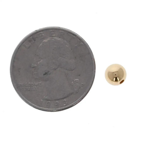 Straight Premium 6MM Gold Filled Round Beads For Jewelry Crafting beside a quarter for size comparison.