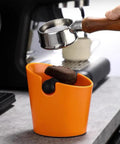 Orange ABS Coffee Knock Box 2.5L Open Top With Non Slip Base shown on countertop with portafilter knocking out grounds