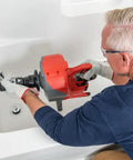 Person using Heavy Duty Cordless Drain Snake With Brushless Motor And Twenty Five Foot Steel Cable to clear a tub drain.
