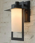 Top Tier Modern Outdoor Wall Sconce Featuring Waterproof Black Matte Aluminum Bracket And Cylindrical Glass Shade on a wall.