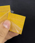 Hand holding Soldering Lugs Rework Pad Set For Phones And IC Pads No Fuss Easy Welding Point Repair yellow pad with peel-off layer