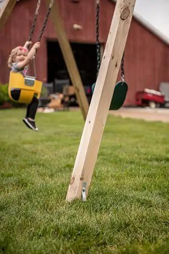Playset Anchor Kit For Swing Sets Heavy Duty Ground Anchors visible on wooden swing set installed in a grassy backyard.
