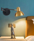 Industrial Metal Swing Arm Wall Sconce With A Sleek Dome Shade And Knockout Build For Cozy Bedroom Or Living Room Reading Vibes E27 Socket Modern Wall Fixture Black Brass Finish mounted above a nightstand.