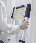 Person holding Telescoping Aluminum Ladder 10.5 Foot With One Button Retraction Collapsible Extension Ladder indoors