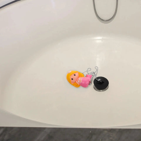 Mermaid Rubber Tub Stopper with Chain for Bathtub Drains lying in a white bathtub, featuring a colorful mermaid design.
