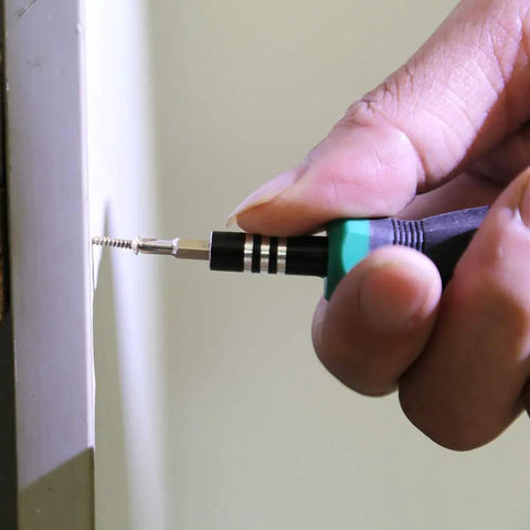 Hand using a screwdriver with a 1600 Pc Heavy Duty Mini Screws 2.5 X 6 8 10 mm Phillips Flat Head to install a screw.