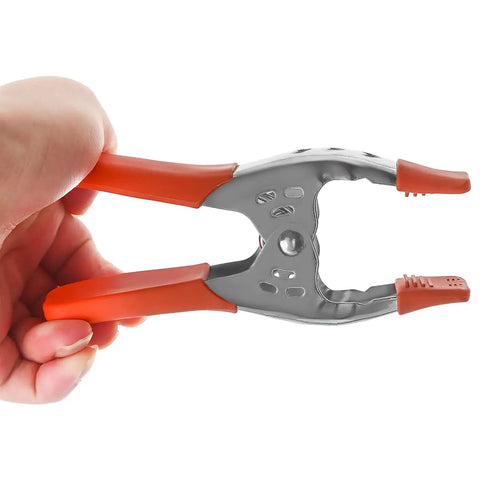Hand holding a clamp from the Twenty Four Pack Of Heavy Duty Six Inch Spring Metal Clamps With 2.5 Inch Jaw Opening, Nickel Plated Steel For Carpentry.