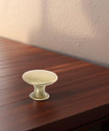 Single gold vintage round knob from Six Pack Round Drawer Knob Pulls With Screws Gold Vintage Dresser Cabinet Knobs For Kitchen Cabinets And Wardrobe Hardware With Easy Grip Decorative Versatile, resting on a wooden surface.