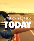 Person in a car reaching out with the text 'Wrench Your R/C Today' during a scenic sunset drive on an open road.