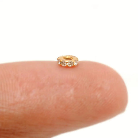 Totally Legit 14k Solid Yellow Gold Pave Diamond 4mm Wheel Spacer Bead on a fingertip for charm bracelets and necklaces.
