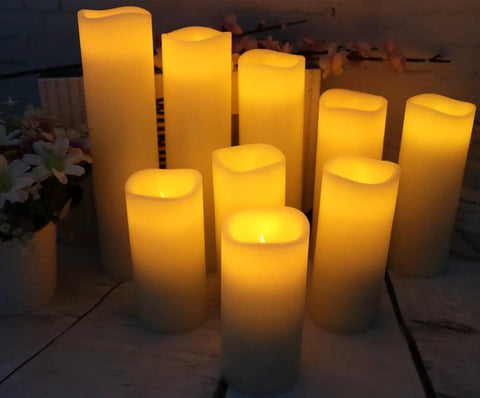 Nine Piece Flameless LED Wax Pillar Candles Set With Remote Timers Real Wax Ivory Finish displayed glowing on a table
