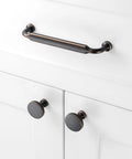 Top Shelf Round Oil Rubbed Bronze Cabinet Knobs 1 1/4 Inch installed on white cabinet doors with matching pull handle.