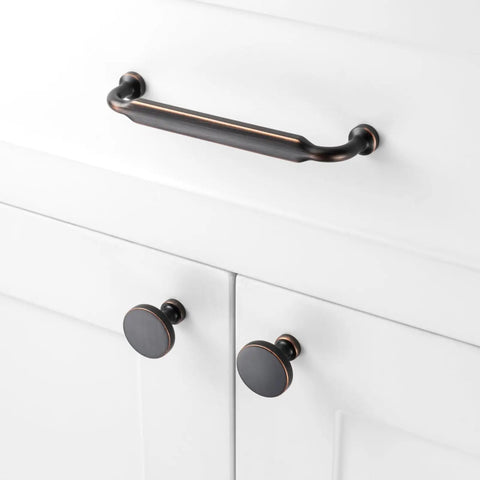Top Shelf Round Oil Rubbed Bronze Cabinet Knobs 1 1/4 Inch installed on white cabinet doors with matching pull handle.