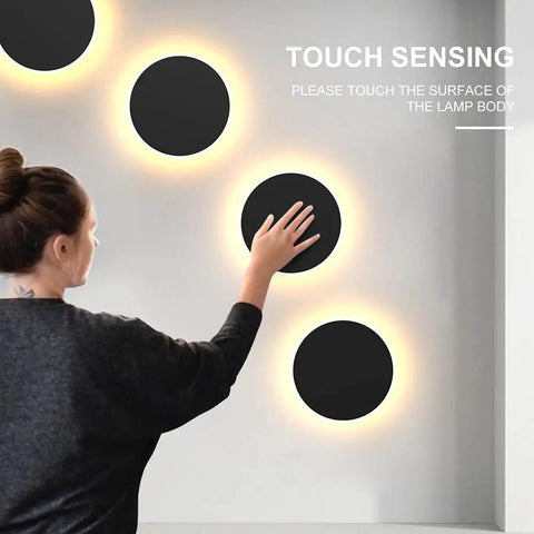 Woman interacting with Modern Black Touch Sensor LED Wall Sconce 10W 3000K Hardwired Indoor Light, sleek circular design on wall.