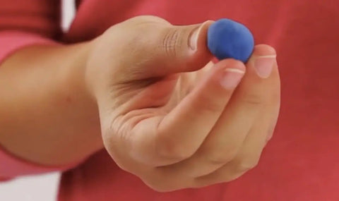 Person holding a blue beeswax earplug for deep sleep and snoring reduction so you sleep like a boss with custom molded fit soft and pliable