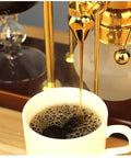 Premium Manual Coffee Brewer With Heat Proof Borosilicate Glass And Food Safe Stainless Steel Pour Over Set For Home Office Smooth Sipper Game Changer Gold Edition pouring coffee into a white cup.