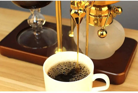 Premium Manual Coffee Brewer With Heat Proof Borosilicate Glass And Food Safe Stainless Steel Pour Over Set For Home Office Smooth Sipper Game Changer Gold Edition pouring coffee into a white cup.