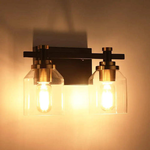 Slick Two Light Industrial Style Bathroom Vanity Light With Clear Glass Shades Matte Black Finish And Brushed Bronze Copper Accent Sockets E26 Bulb Compatible Non Dimmable Fixture Modern Wall Mount Bath Lighting lit view