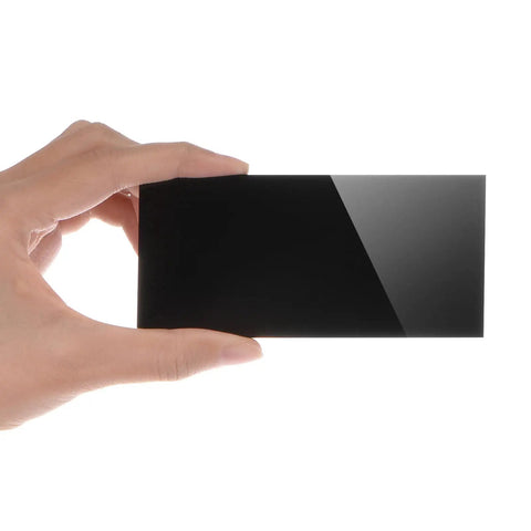 Hand holding a Two Pack Shade 10 Welding Lens Replacement 2X4.25 Inch Hardened Frosted Black Filter Plate for helmets.