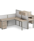 Dual L Shaped Office Cubicle Workstation With Roll Along File Cabinet And Chill Gray Desktop Layout For Squad Collaboration and Hassle Free Daily Workflow Management, featuring light wood surfaces and dividers.