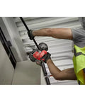 Worker using M12 Fuel Compact Cordless Band Saw With 2.5 Inch Throat Depth And 30.56 Inch Blade for cutting metal pipe overhead.