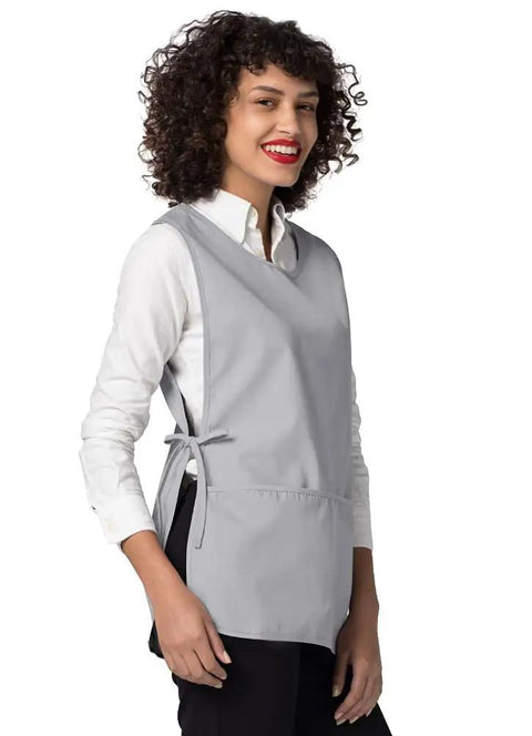 Heavy Duty Cobbler Apron Set Of Six With Deep Front Pockets And Adjustable Waist For Nurses Crafters And Mechanics Works Like A Champ Built Tough For The Daily Grind In Sharp Silver Gray worn by a smiling woman with curly hair.