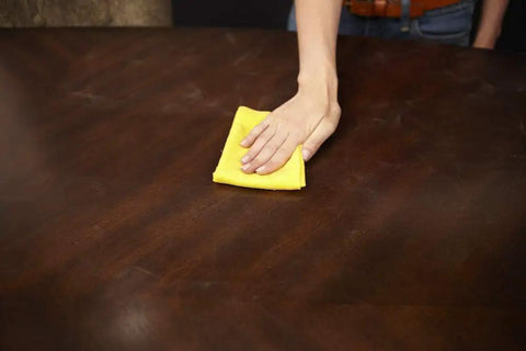 Person using Game Changer Pre Treated Wood Furniture Dusting Cloths Pack Of Five Lint Free Wipes on a wooden table.