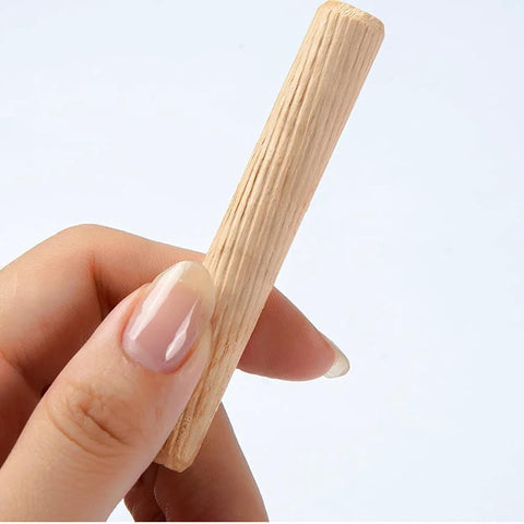 Hand holding a grooved wooden dowel, part of the 21 Pieces Hardwood Grooved Wooden Dowels Assorted Sizes M6 M8 M10 set for carpentry projects.