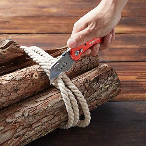 Amazon Basics folding utility knife with red aluminum handle; close-up cutting rope around logs