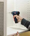 Person using 12V Max Two Speed Pocket Driver Bare Tool With 265 Inch Pounds Torque And 1300 RPM Ultra Compact Five Point Six Inch Head Lightweight Tool For One Hand Quick Jobs inside cabinet