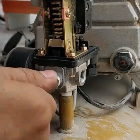 Close-up of a four-port air compressor pressure switch control valve with a red on/off knob being installed on a compressor unit.
