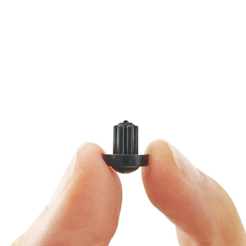 Close-up of a single Heat Resistant Durable Non Slip Rubber Grate Feet For Gas Stove Top Cooktop Replacement Pads held between fingers.