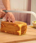 Adjustable Cake Leveler And Wire Slicer For Even Layer Cakes Pro Grade Stainless Steel Cutter in use on a sponge cake
