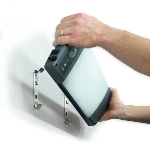 Hands installing Outdoor Solar LED Area Light With Motion Activation And USB Charging No Wiring Needed 8800mAh Battery Delivers 15 Plus Hours Runtime 360 Degree Motion Sensor Portable Weatherproof Black And Gray onto wall brackets
