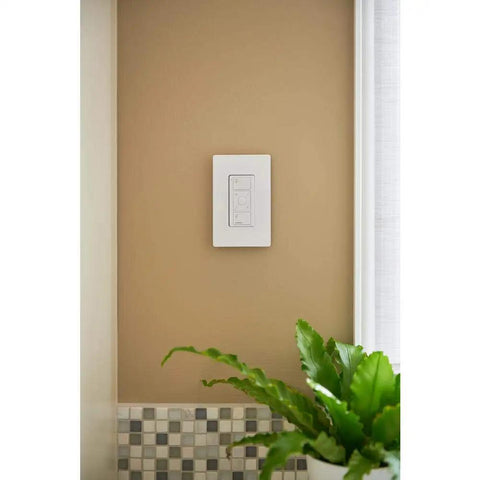 Caseta Wireless Pico Remote Wall Mount Kit For 3 Way Smart Dimmer Setups installed on a beige wall above a plant
