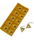 Twenty carbide turning inserts in a yellow plastic storage tray; triangular with center holes (TCMT32.51/32.52/16T304/16T308)