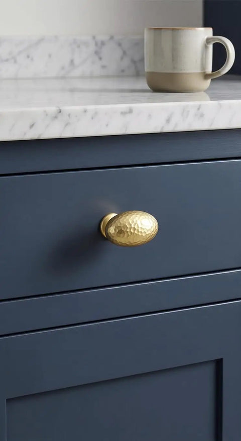 Top Shelf Champagne Bronze Cabinet Knobs With A Hammered Oval Dome and Soft Metallic Luster on blue drawer, quick install.