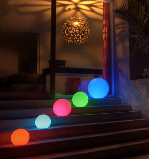 Five Ultra Fun Waterproof 10 Inch RGB LED Ball Light Orbs on steps with colored glow at night, perfect for outdoor decor.
