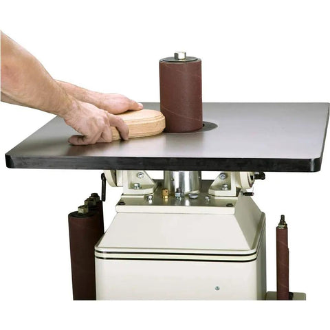 Powerful One Horsepower Oscillating Spindle Sander featuring rock solid cast iron table, hands placing wood on sander.