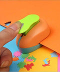 Hand using Spring Action Five Eighth Inch Circle Paper Punch For Crafting, cutting shapes from orange paper