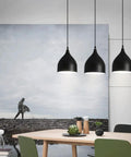 Dark Antique Farmhouse Pendant Light with Single Hanging Shade over a dining table, showcasing its rustic black design.