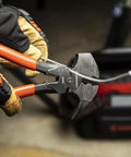 Close-up of Heavy Duty Solid Joint Fence Tool Pliers, 10 Inch, Ergonomic Dipped Handle, Pro Grade Hand Tool in use by a person wearing gloves